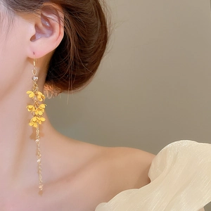 Detailed close-up of long yellow flower beaded tassel earrings worn by a model
