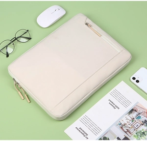 Flat lay of beige laptop sleeve with accessories on a soft green desk background