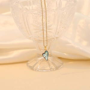 Detail of light blue heart crystal pendant with gold edge on elegant satin background