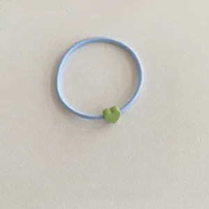 Macro di un elastico per capelli celeste con un ciondolo a forma di cuore verde opaco