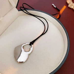 Close-up of a silver hollow double heart pendant necklace in a round jewelry box