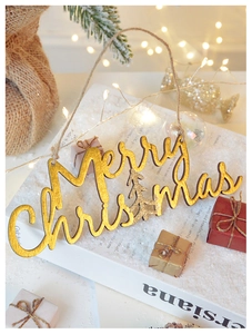 Detail of gold Merry Christmas wooden tag with glitter and twine on a snowy background