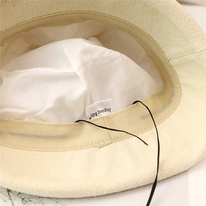 Dettaglio interno del cappello a secchiello in maglia beige con fodera e fascia tergisudore