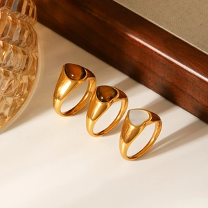 Detail of 18k gold rings with heart-shaped tiger eye and white shell inlays