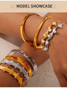 Detailed view of layered gold and silver cuff bracelets with pearl accents on model