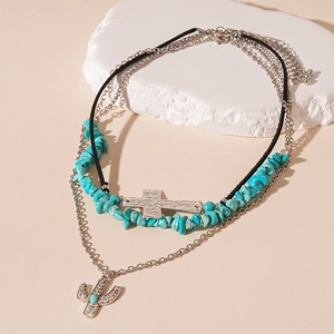 Detail of multi-layer necklace featuring turquoise beads, silver cross and cactus charms