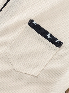Detail of waffle knit fabric and pocket with navy piping and bird print on men shirt