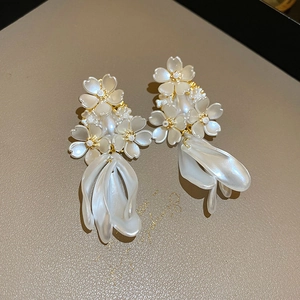 Detailed view of pearl white floral earrings with golden accents and hanging resin petals
