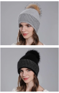 Detail of winter knit beanies in grey and black with fluffy fur pom-poms and silver stripes