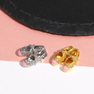 Detailed macro view of gold and silver ballet slipper charms with pink tips and zircons