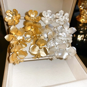 Detailed macro view of matte brushed flower earrings in gold and silver finish