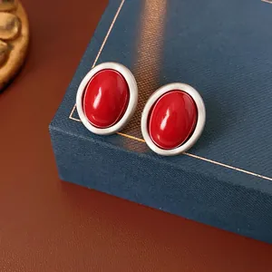 Minimalist red oval enamel stud earrings with matte silver frames in a jewelry box