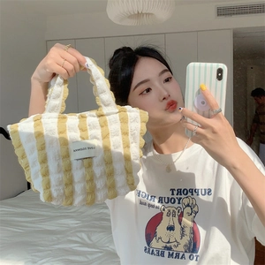 Detail of yellow and white striped bubble fabric tote bag with a woven brand logo label