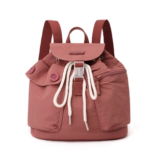 Detail of red nylon backpack showing drawstring closure and brand logo on the front flap