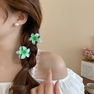 Detail of sweet gradient green sunflower hair claws on a braided hairstyle with pearls