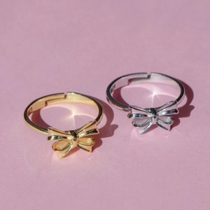 Bow tie rings in gold and silver finish made of S925 sterling silver on pink surface