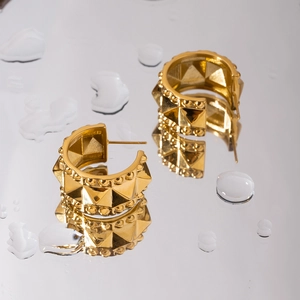 Macro shot of gold-plated stainless steel C-shaped earrings with pyramid stud texture