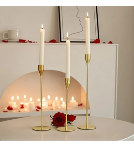 Close-up of three gold metal candle holders in different heights with burning candles