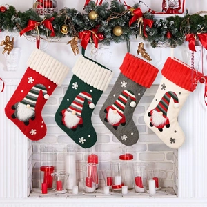 Close-up of knitted Christmas stockings with gnome 3D decor hanging on fireplace