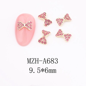 Macro detail of gold bow nail charms with pink zircons and 9.5x6mm size measurement