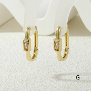 Macro shot of gold geometric earrings with rectangle-cut white zircon on a clean white desk