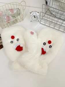 Detailed view of white plush snowman mittens with red hats on a cozy tabletop