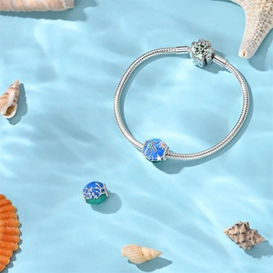 Close-up of ocean-themed airplane charm bead on blue water with seashells background