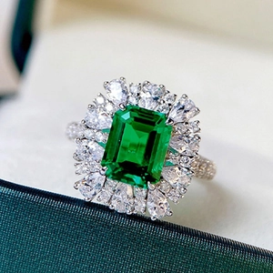 Silver ring with emerald cut green gemstone and white zircons on velvet jewelry box