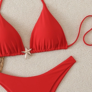 Detail view of red bikini top featuring a golden starfish buckle on textured fabric