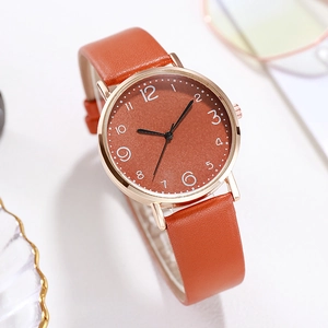 Détail d'une montre de mode avec bracelet en cuir orange et boîtier rond en or rose