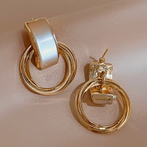 Vintage gold metal geometric earrings with faux cat eye stone on beige fabric background