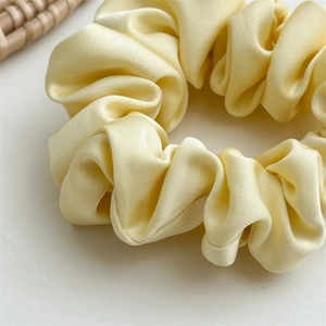 Detailed view of cream yellow satin scrunchie showing soft silky texture and folds