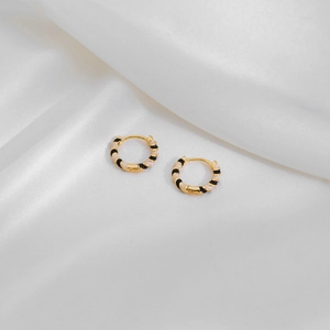 Detail of gold geometric hoop earrings with black and white enamel textures on silk