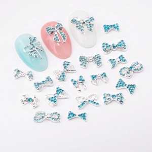 Bijoux d'ongles en forme de nœud argenté avec strass bleu clair sur faux ongles