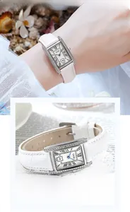 Detailed macro view of square silver watch with crystal bezel and white leather strap