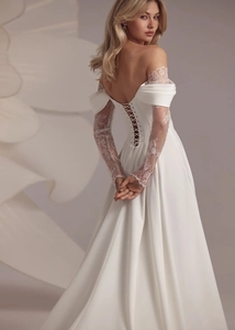 Detailed view of the lace-up back and white lace sleeves on an elegant satin wedding dress