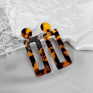 Detail of amber tortoiseshell pattern acrylic earrings on white silk and glass