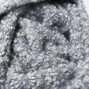 Close-up texture of a thick grey-white boucle knit beanie for winter outdoor warmth