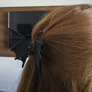 Detail of matte black bat wing hair claw clip worn on a ponytail for gothic styling
