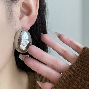 Macro view of large polished silver oval bean earrings with high-gloss mirror finish