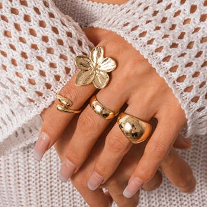Three-piece gold geometric ring set with flower and serpent designs on woman's hand