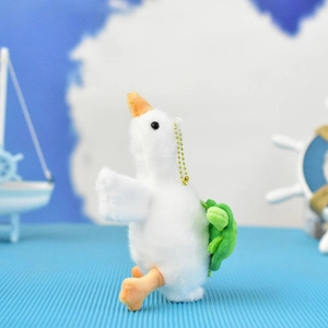 Side view of cute plush white goose keychain with green turtle backpack accessory