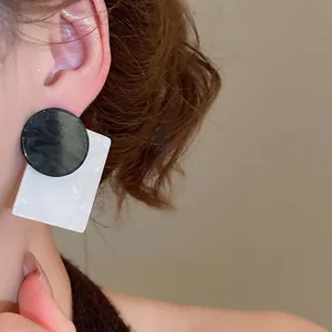 Modern black circle and white rectangle shell drop earrings shown on a female model