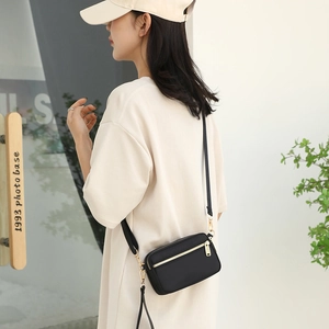 Compact black crossbody bag with multiple zip compartments and adjustable shoulder strap