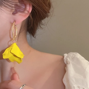Close-up of yellow flower petal earrings with golden irregular metal ring on model