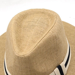 Macro detail of natural straw fedora hat featuring fine weave and striped ribbon band