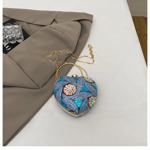 Macro detail of heart-shaped evening bag with sequin floral embroidery and gold chain