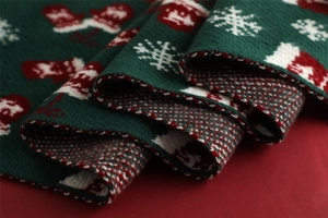 Close-up of dark green knitted Christmas scarf featuring red and white snowflake patterns