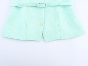 Détail du tissu en tweed vert menthe avec ceinture et bouton doré brillant