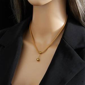 Close-up of golden snake chain necklace with circular pendant on black blazer